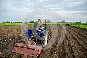 A farmer cultivates a field with a tractor after harvest. Milling soil, crushing before cutting rows. Farming, agriculture