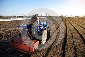 A farmer is cultivating the farm field. Seasonal worker. Recruiting workers with driving skills of agricultural machinery. Work in