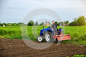 A farmer with a cultivation unit on a tractor rides to cultivate a field. Milling soil, crushing before cutting rows. Agribusiness