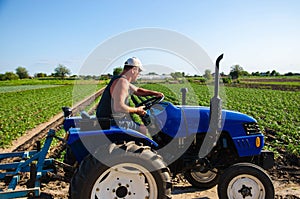 The farmer drives a tractor on the farm. Agroindustry and agribusiness. A man driver works in the field. Farm machinery