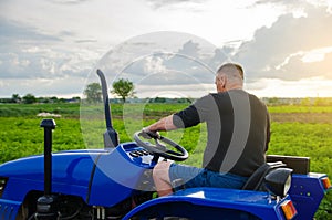 Farmer drives a tractor. Harvesting crops campaign, earthworks. Agroindustry and agribusiness. Countryside farmland. Farming.