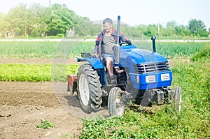 A farmer drives a tractor while working on a farm field. Loosening surface, cultivating the land. Farming, agriculture