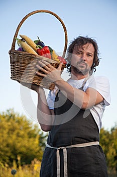 Farmer with an ecological harvest of vegetables in a basket near