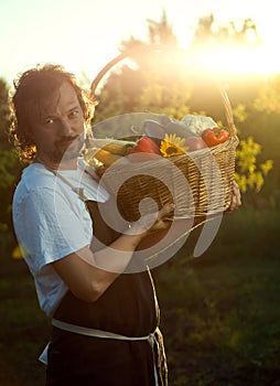 Farmer with an ecological harvest of vegetables in a basket near