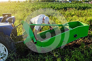 A farmer examines a machine for digging out potato root vegetables. Exploitation and maintenance of equipment. Farming agriculture