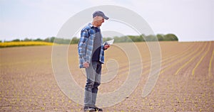 Farmer Examining Agricultural Field While Working on Digital Tablet Computer at Farm.