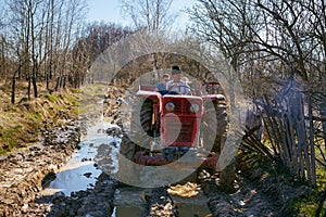 Farmer family driving a tractor on a muddy rural road