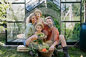 Farmer family with fresh harvest sitting in a greenhouse