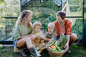 Farmer family with fresh harvest sitting in a greenhouse