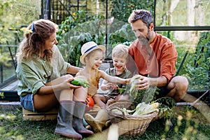 Farmer family with fresh harvest sitting in a greenhouse