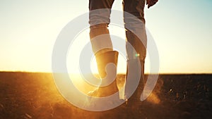 farmer feet walks across a black field. agriculture business concept. silhouette of a farmer feet at sunset walking