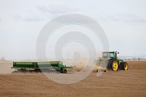 A farmer in a field, planting wheat.