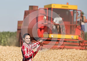 Farmer girl and combine harvester in wheat field
