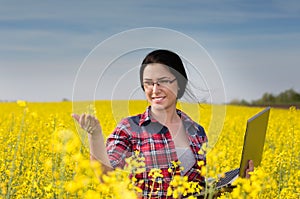 Farmer girl with laptop in rapeseed field