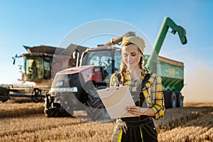 Farmer on grain field with tractor and combine harvester in background