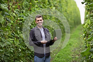 A farmer on a green field looks at the camera and smiles. Happy farmer