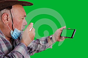 A farmer with a green screen smartphone is suffering from a grueling cough.