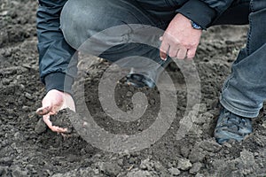 Farmer hands digging ground in spring in field