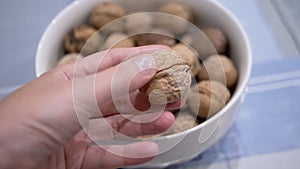 Farmer Hands Takes and Holding One Nut from a Full Bowl of Walnuts on Table. 4K