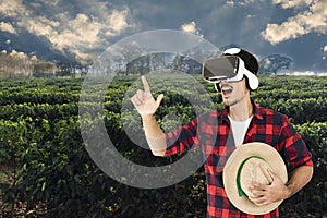 Farmer with hat and virtual reality glasses on coffee plantation landscape