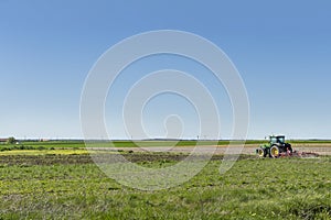 A farmer with her tractor plowing a field in a flat area of â€‹â€‹Castilla, Spain