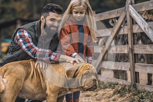 Farmer and his daughter caressing their dog