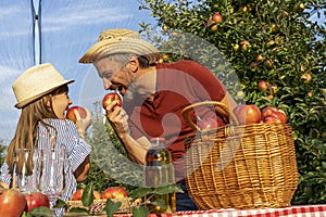 Farmer and His Daughter Eating Apples and Having Fun in Sunny Orchard