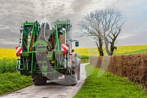 farmer and his tractor equip with a sprayer leaving for work in the spring photo