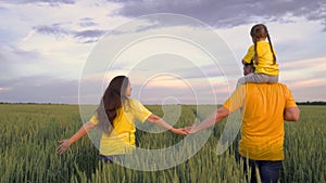 a farmer with his wife and a little kid on his shoulders walks in a green wheat field, a happy family, a child's dream