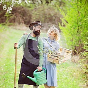 A farmer and his wife standing in their field. Farmars couple enjoy spring nature and take care about her plants. Earth