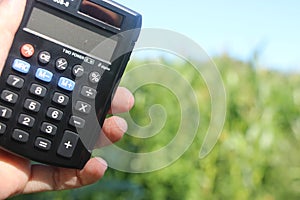 Farmer holding Calculator in hand calculate production field. Business concept