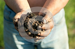 Farmer holding lump of wet soil in his hands photo