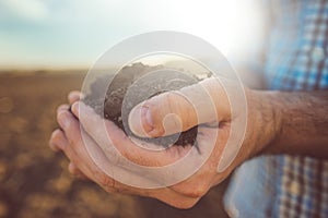 Farmer holding pile of arable soil, close up