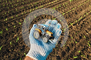 Farmer holding plastic diecast tractor farm vehicle in field photo