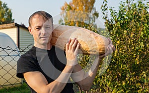 Farmer holds a long yellow pumpkin in his hands
