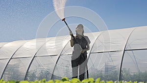 Farmer irrigates of seedlings. Young pretty farmer enjoing her work during irrigating seedlings.