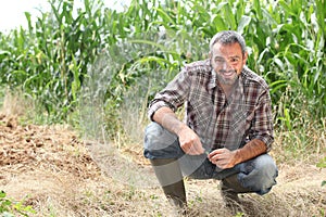 Farmer kneeling by crops