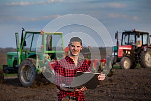 Farmer with laptop and tractors