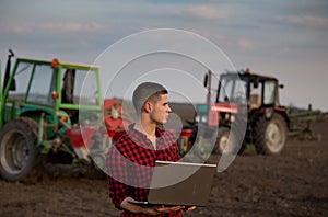 Farmer with laptop and tractors