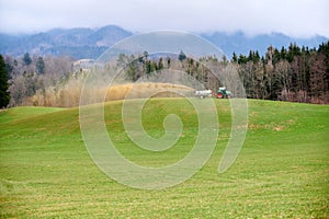 A farmer with a large tractor spreading liquid manure on grassland photo