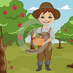 Farmer little boy picking apples holding basket standing in orchard