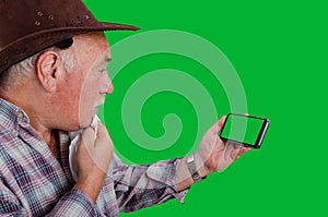 A farmer looks very wary at the green screen of the smartphone.