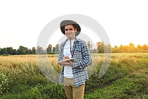 Farmer man. In the midst of a lush green wheat field, a farmer stands holding a tablet in his hands, embodying the