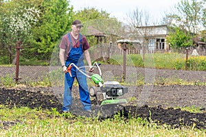 Farmer man plows the land with a cultivator preparing the soil for sowing