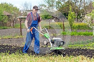 Farmer man plows the land with a cultivator preparing the soil for sowing