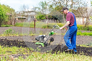 Farmer man plows the land with a cultivator preparing the soil for sowing