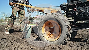 Farmer man works, ploughing garden chernozem field with motorized unit motoblock