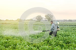 Farmer with a mist sprayer blower processes the potato plantation. Protection and care. Environmental damage and chemical