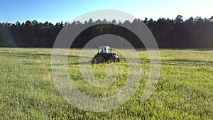 Farmer operates tractor mowing grass for hay on field