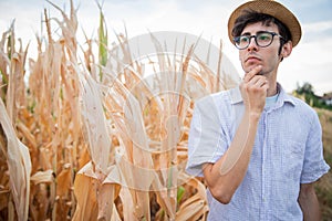 Farmer pensive at the disastrous effects of drought on corn field all burned